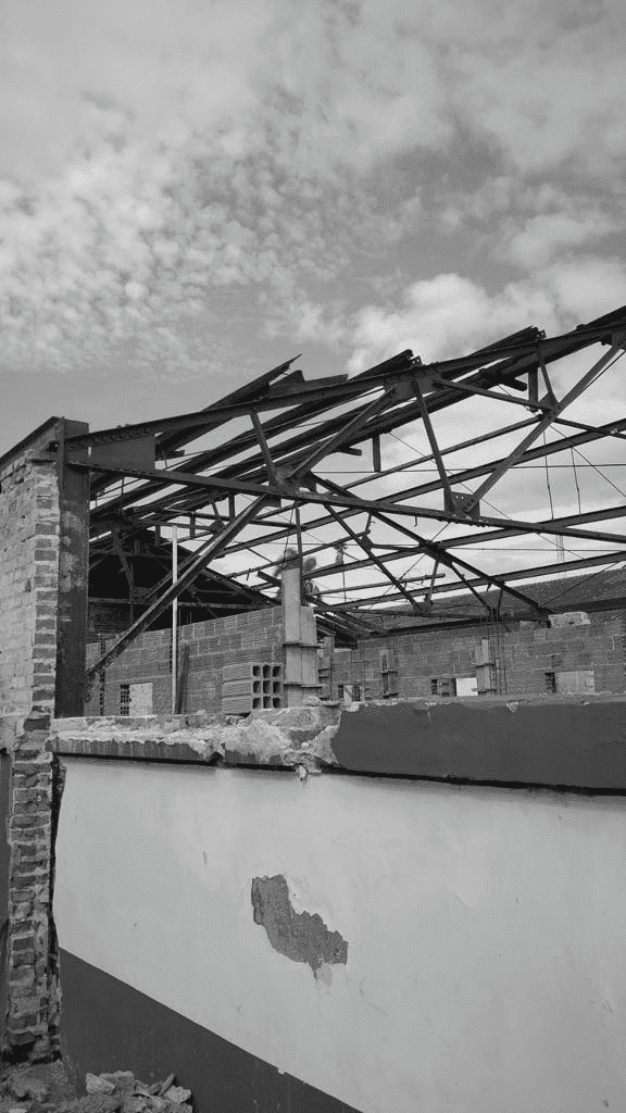 foto preto e branca de uma construção em andamento de um galpão ainda destelhado e com o muro pela metade